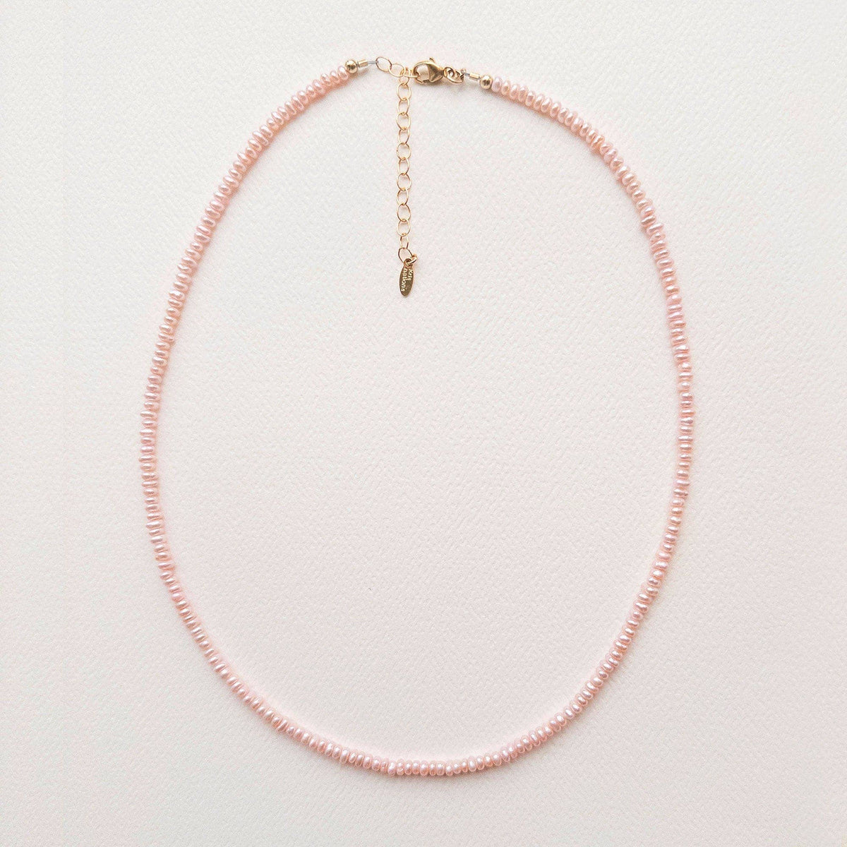 Pink beaded necklace on a light gray background