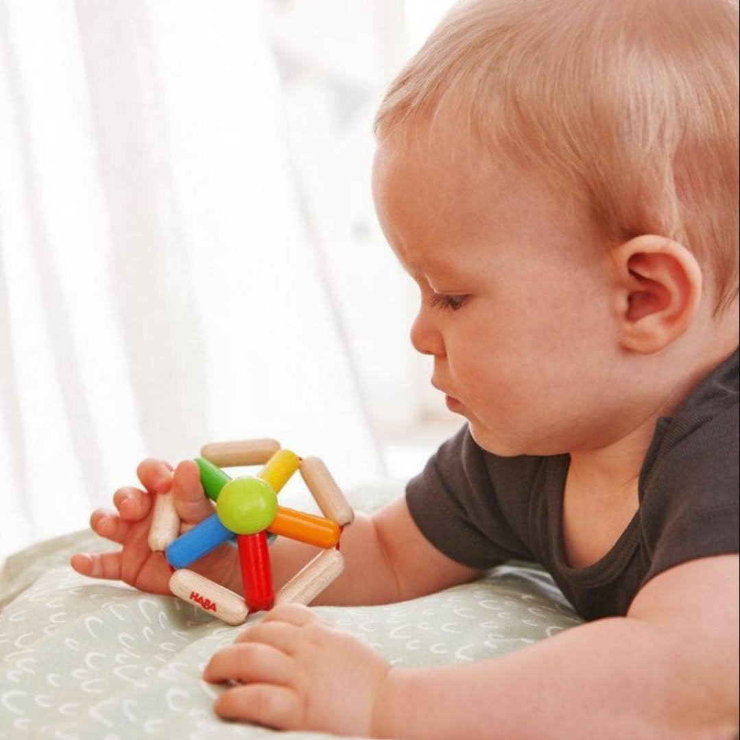 Baby playing with a colorful toy on a light surface