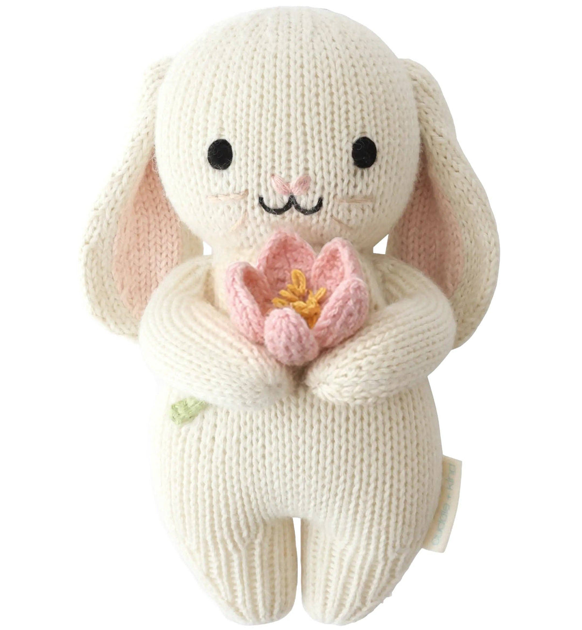 Knitted bunny toy holding a pink flower on a white background