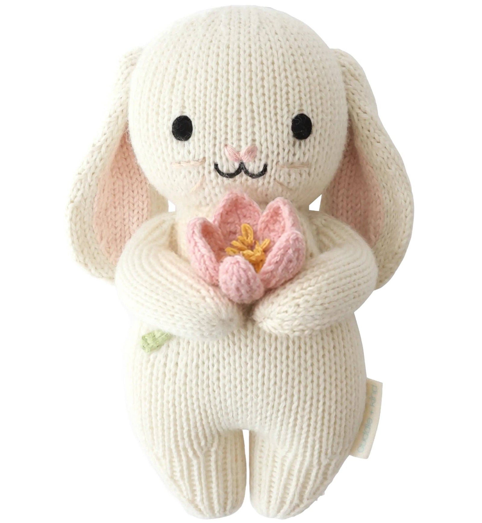 Knitted bunny toy holding a pink flower on a white background
