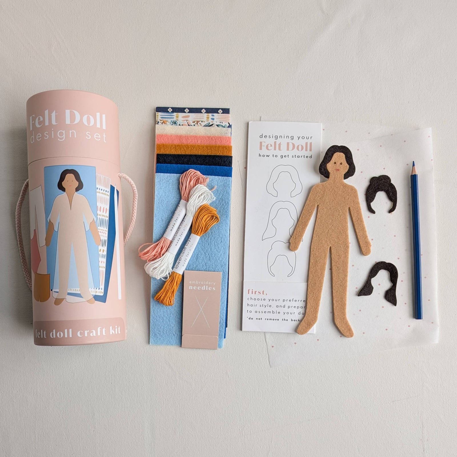 Felt doll design set with packaging, materials, and instructions on a light gray background