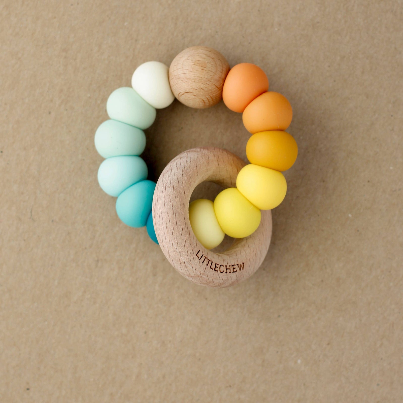 Colorful wooden teething rings on a beige background