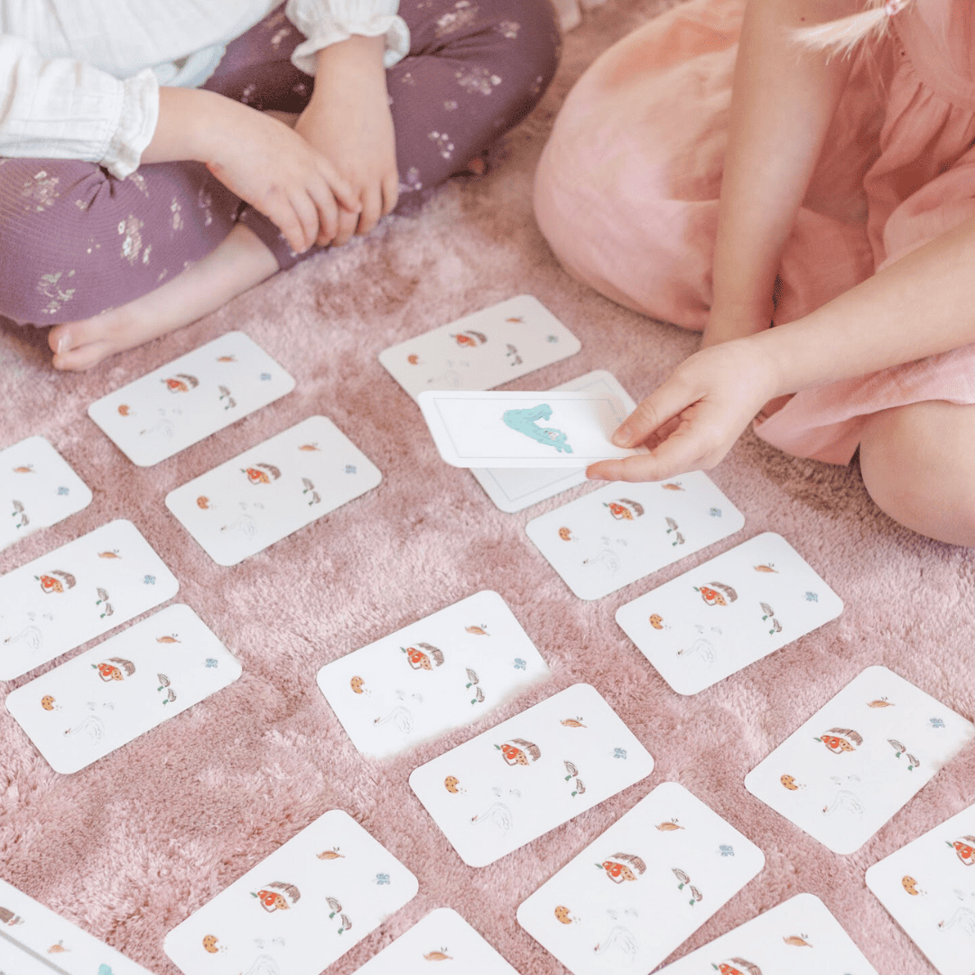 Two children playing with cards on a pink carpet