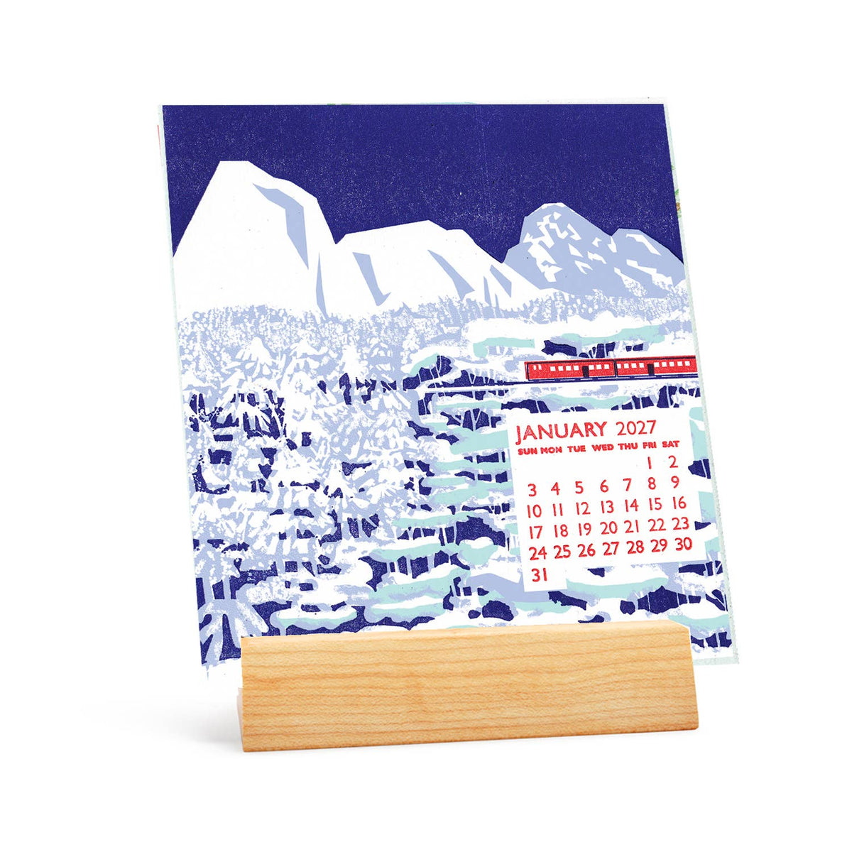 A vertical desk calendar with a winter mountain landscape print in navy blue and white, displayed on a light wood stand against a clean white background.