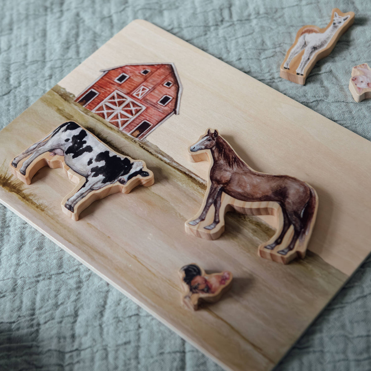 Wooden farm scene with animal figures on a textured surface