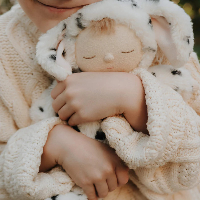 Stuffed animal toy with dog ears on a textured beige blanket
