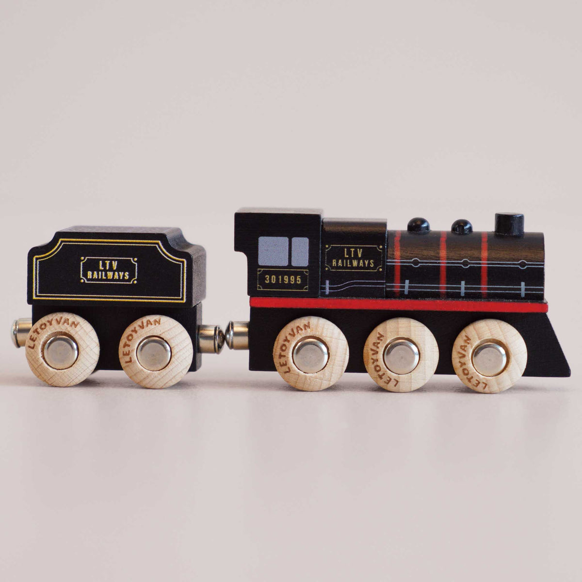 Wooden toy train with black and red design on a light gray background