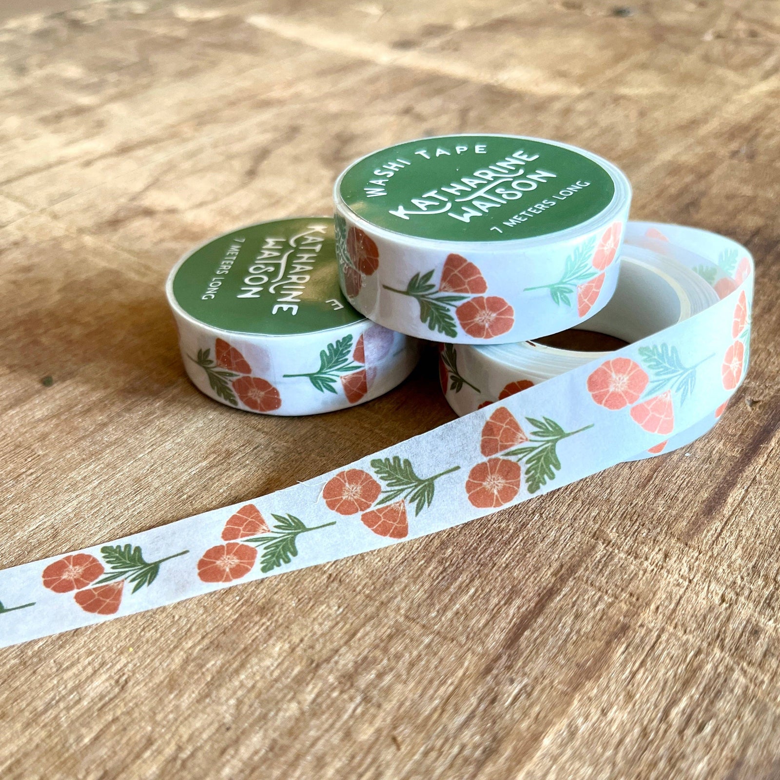 Two rolls of decorative tape with floral designs on a wooden surface