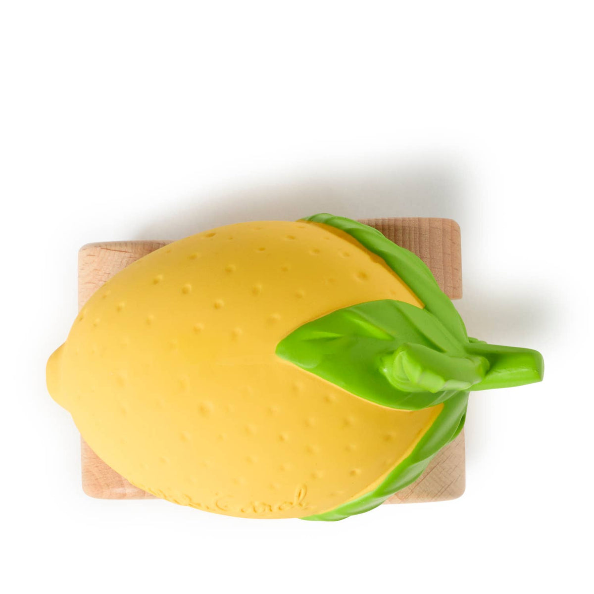 Yellow lemon-shaped object with green leaves on a wooden cutting board against a white background