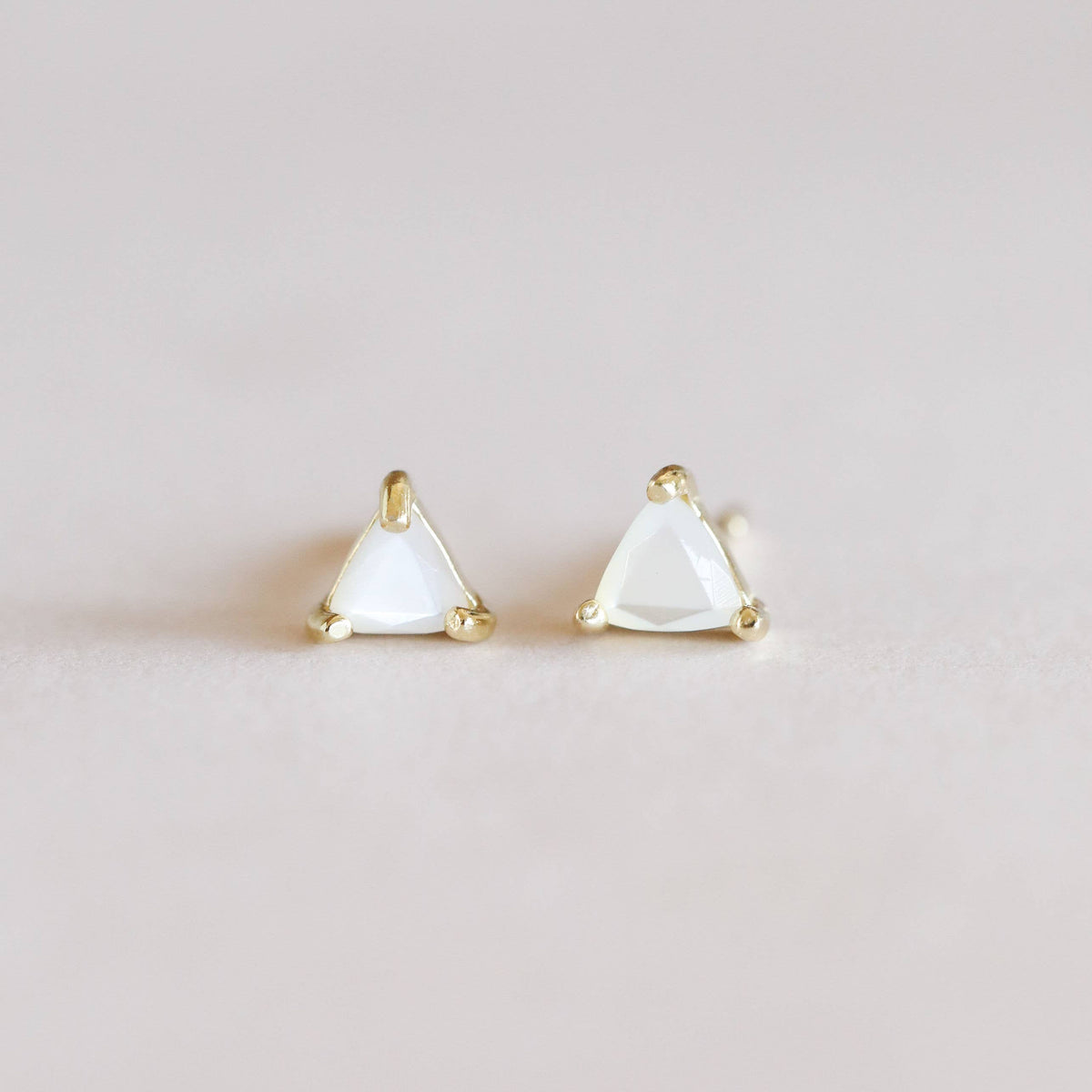 Pair of triangle-shaped earrings on a light gray background