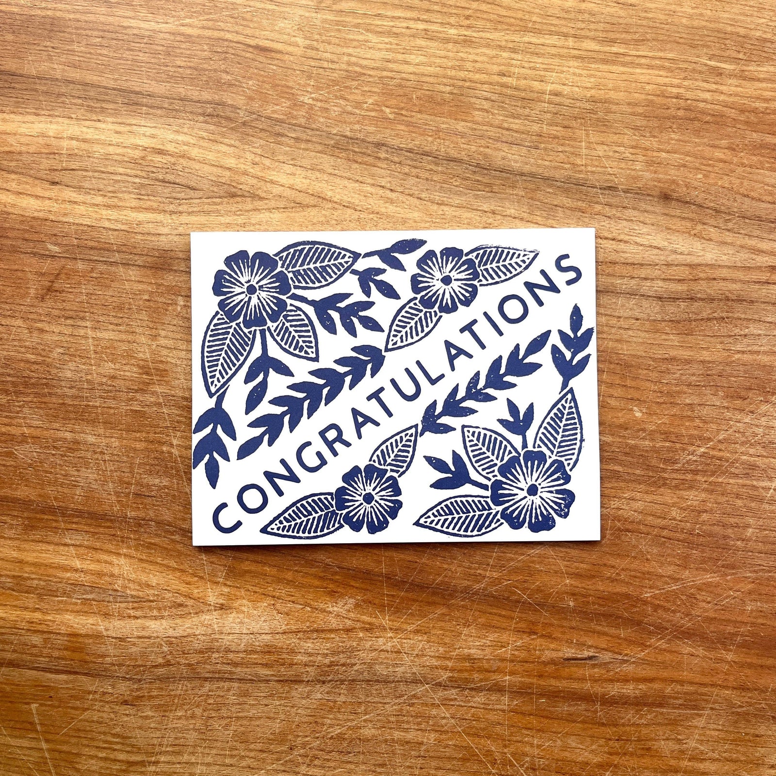 Greeting card with floral design and 'Congratulations' text on a wooden surface