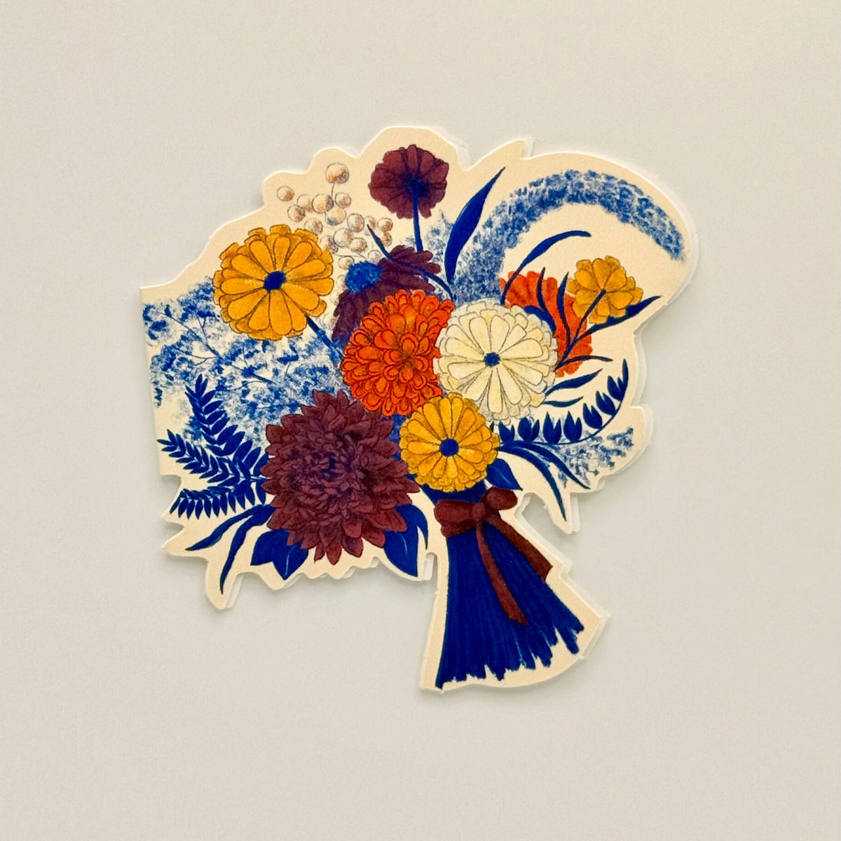 A die-cut card featuring a colorful dried flower bouquet illustration, displayed on a neutral light beige background.