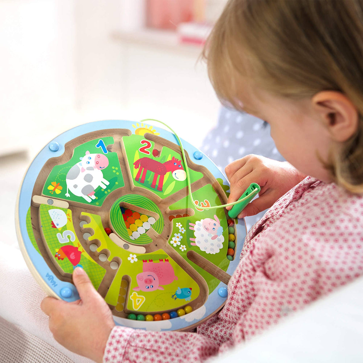 Child playing with a colorful maze toy featuring animals.