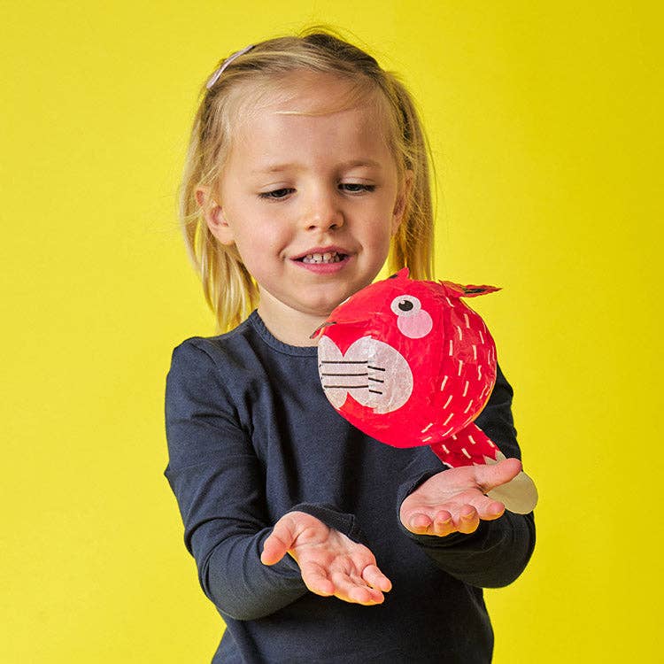 Child holding a red plush toy against a yellow background