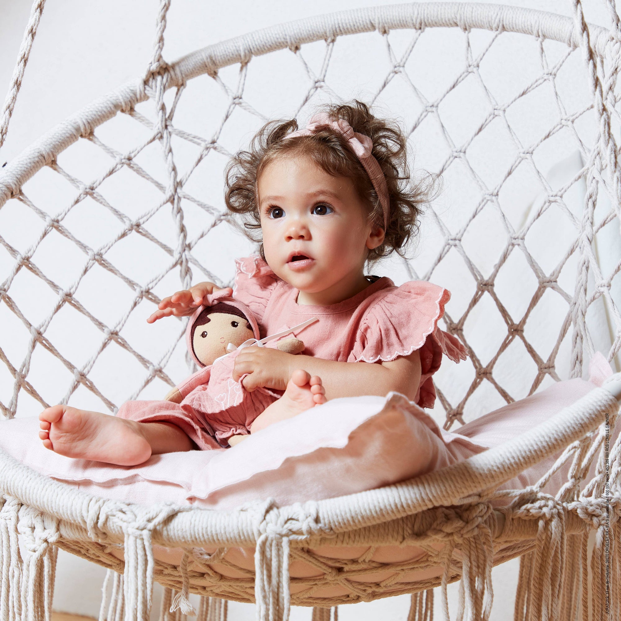 Plush doll in a pink outfit with a matching headband on a white background