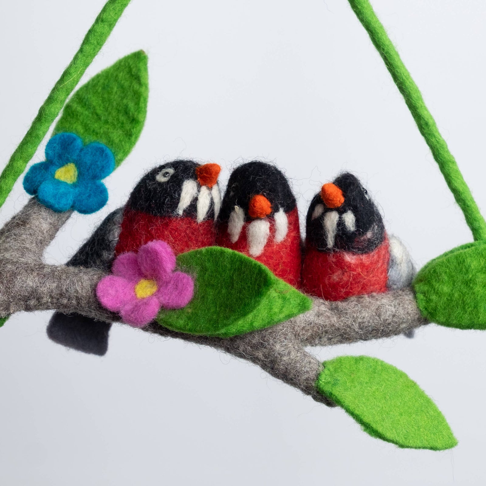 Felt birds on a branch with flowers and leaves against a white background