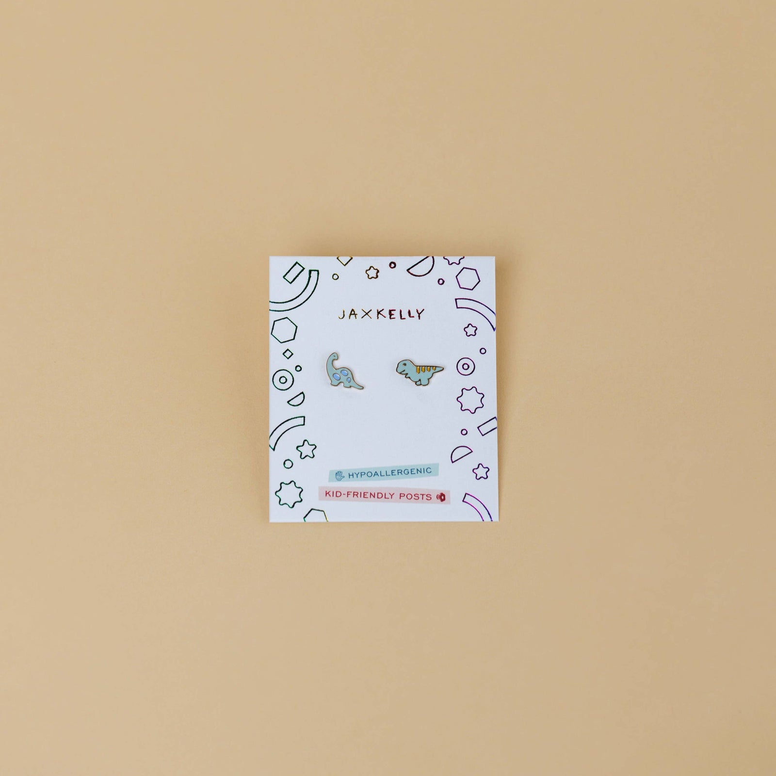 Small card with dinosaur earrings on a beige background