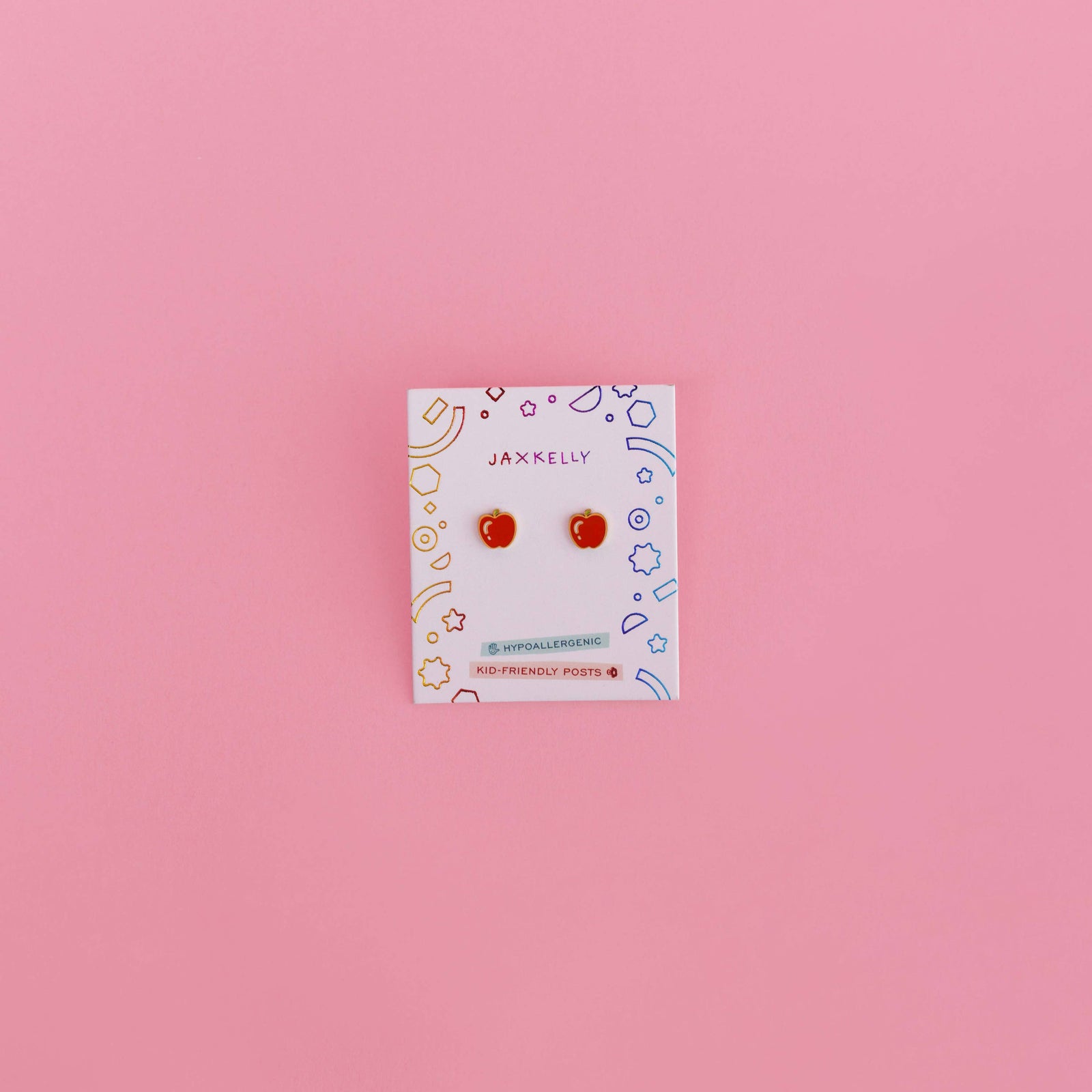 Card with apple-shaped earrings on a pink background