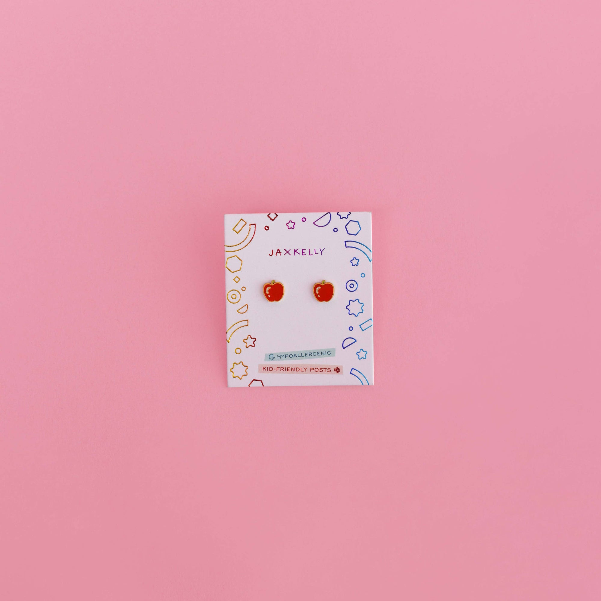 Card with apple-shaped earrings on a pink background