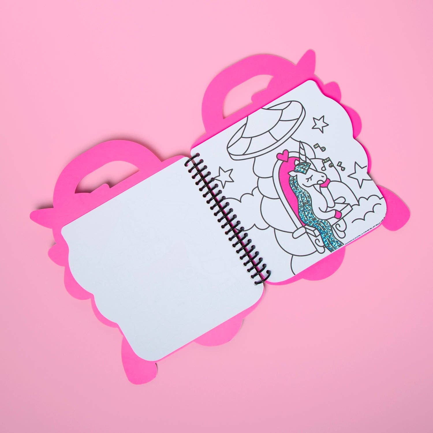 Colorful unicorn-themed coloring book and crayons set on a pink background