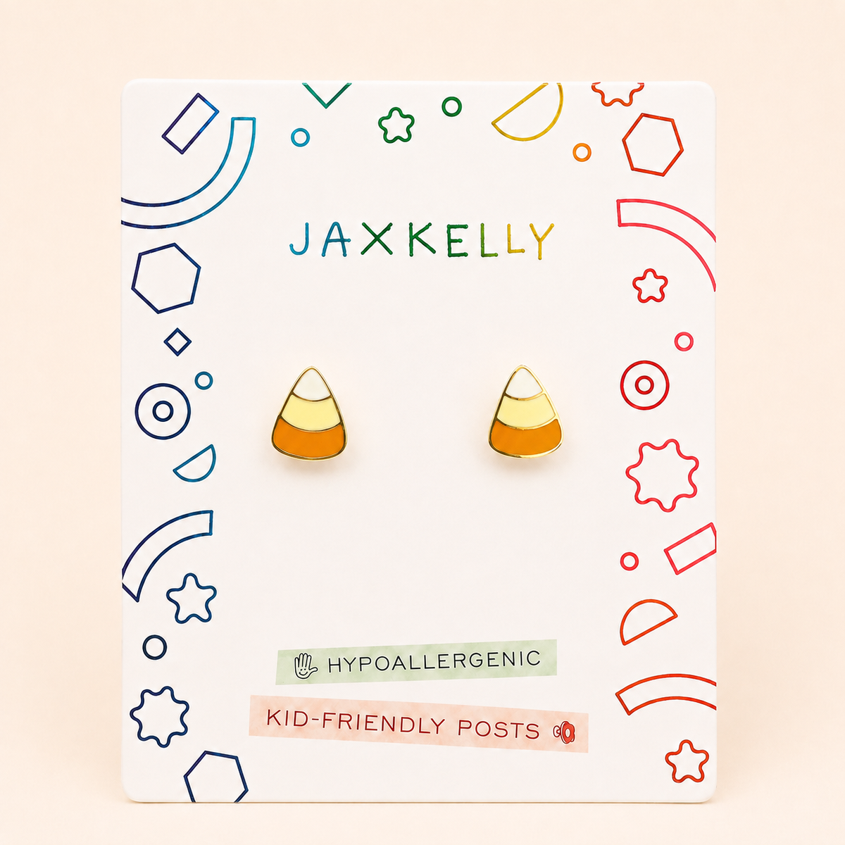A pair of candy corn stud earrings displayed on a white Jaxxelly brand backing card. The earrings feature a classic candy corn design with yellow, orange, and white sections.