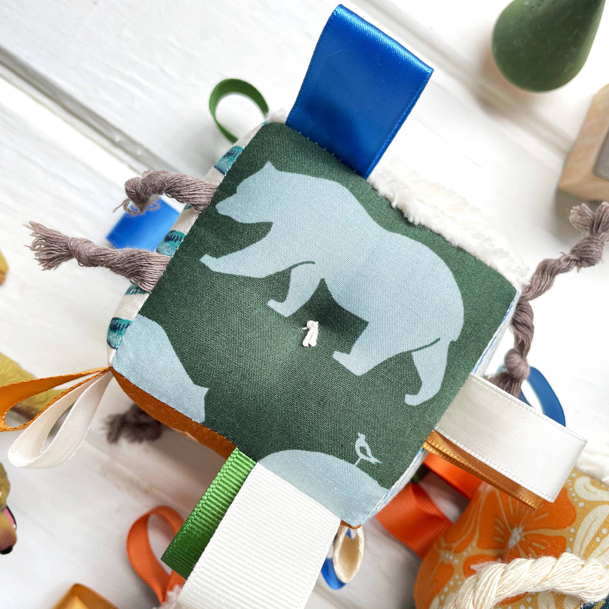 Baby comfort blanket with bear design and colorful ribbons on a white background