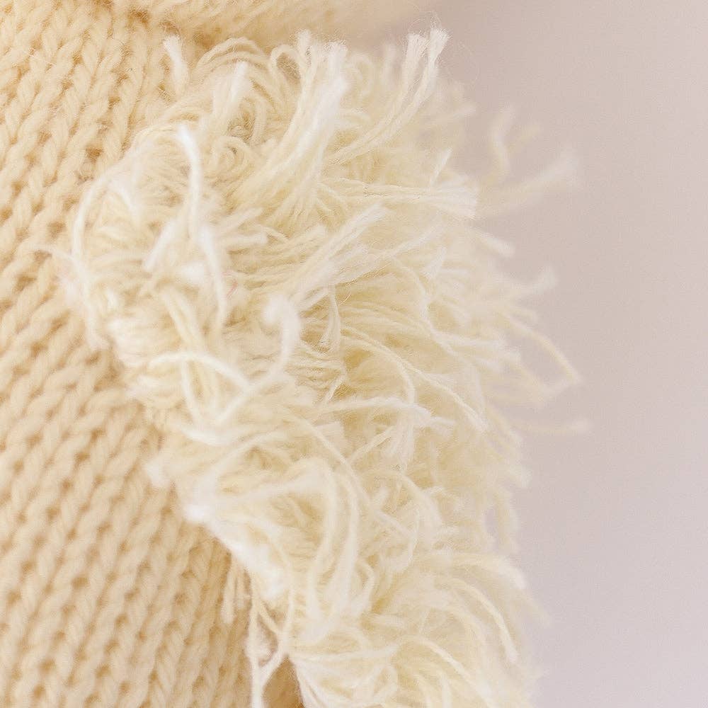 Close-up of beige knitted fabric with frayed edge on a light background