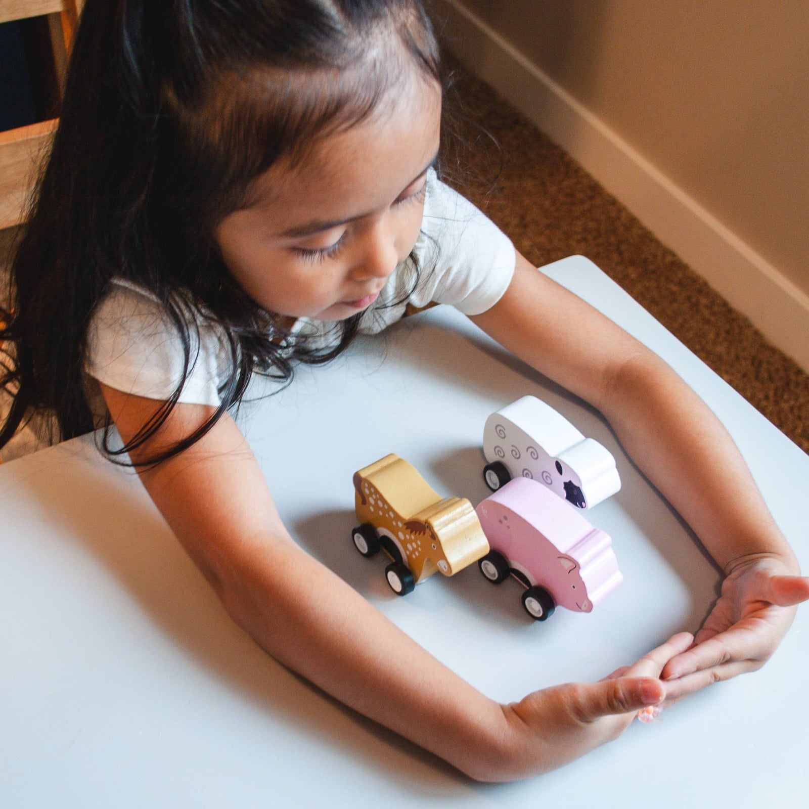 Child playing with toy cars on a white surface