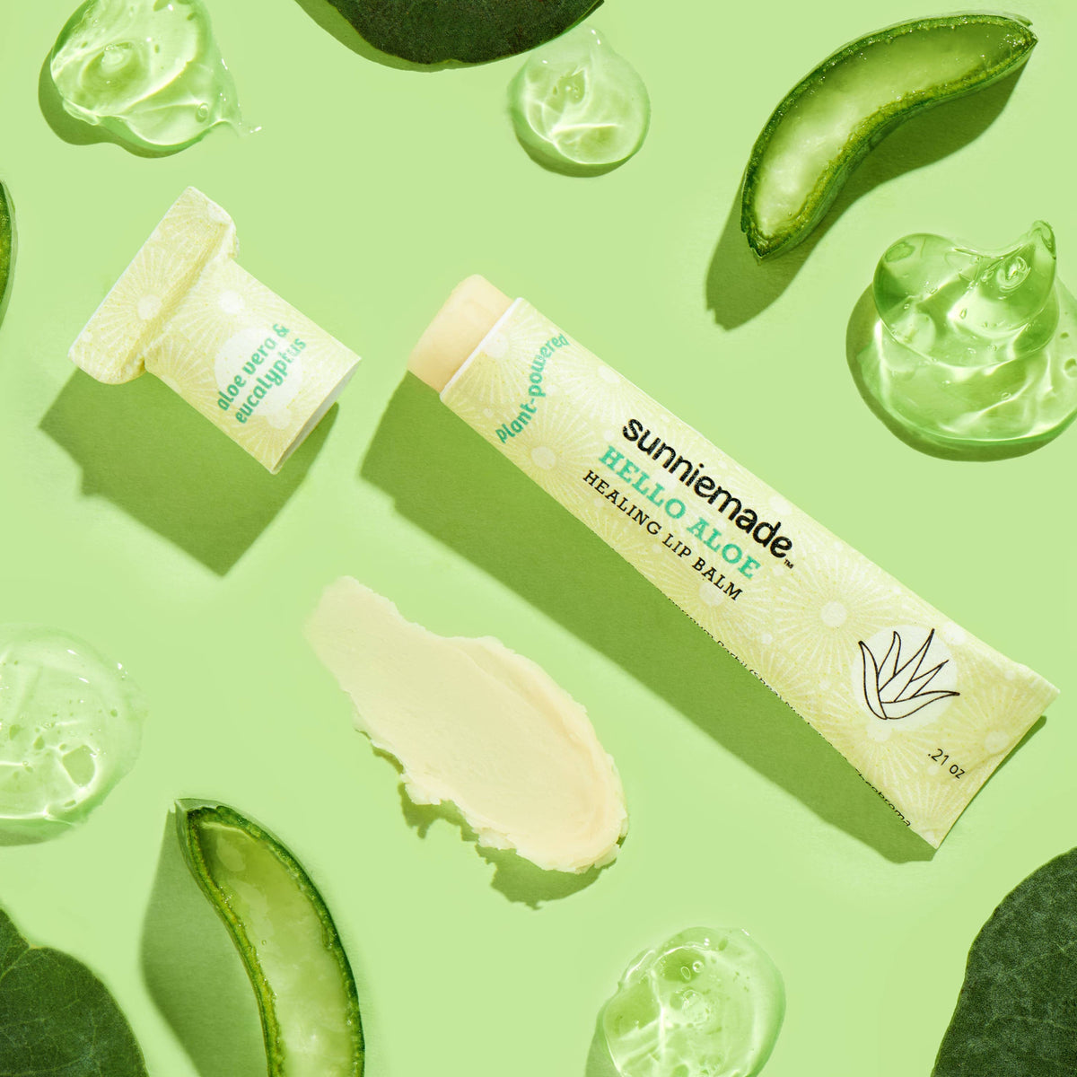 Sunnie Made lip balm with aloe vera slices on a green background