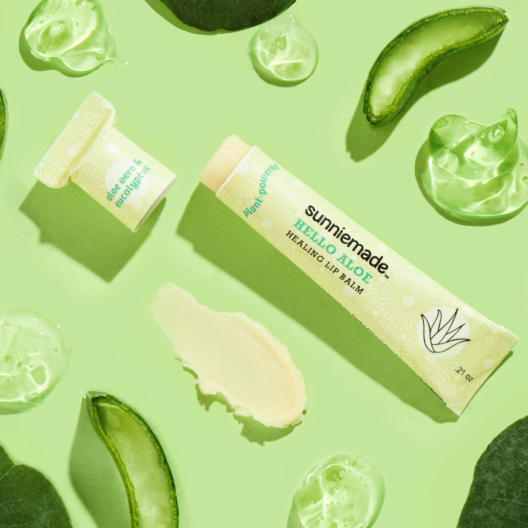Sunnie Made lip balm with aloe vera slices on a green background