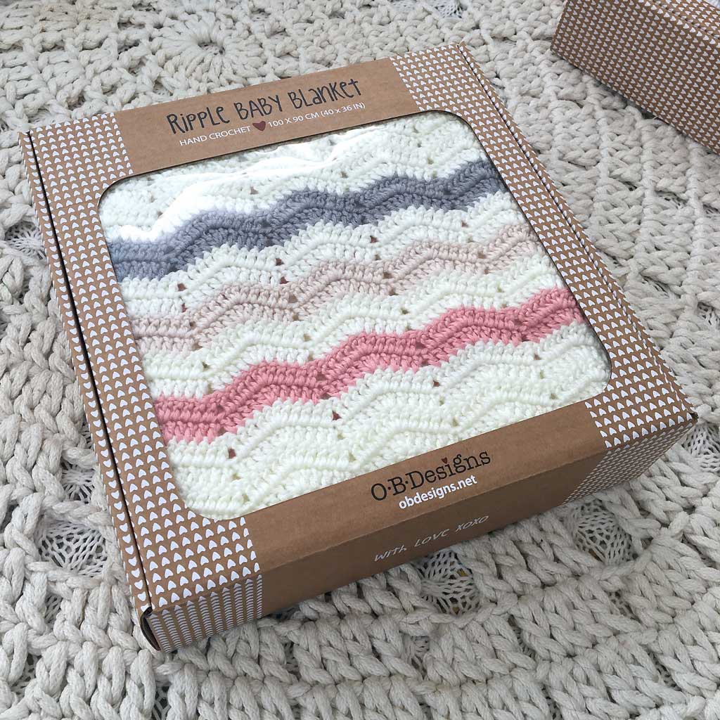 Ripple baby blanket in a brown box on a textured surface