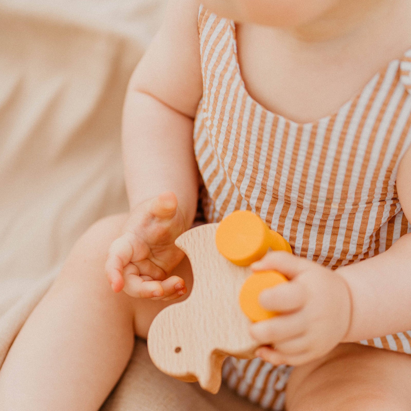 Wooden duck toy with yellow wheels on a white background