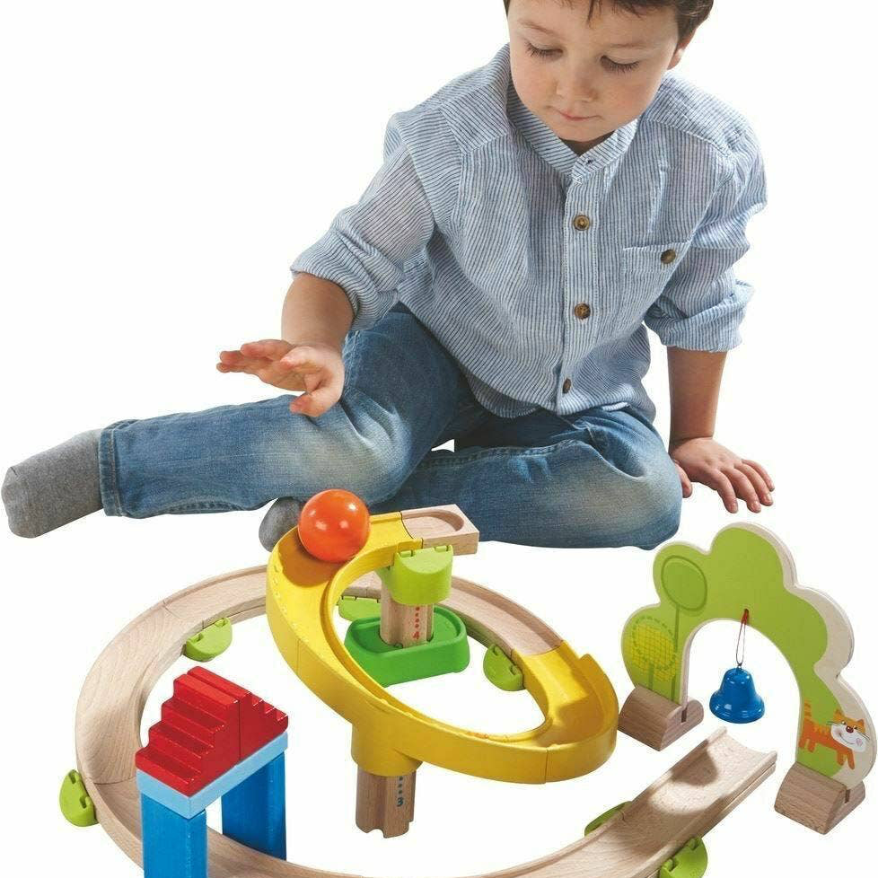 Child playing with a colorful wooden toy train set on a white background