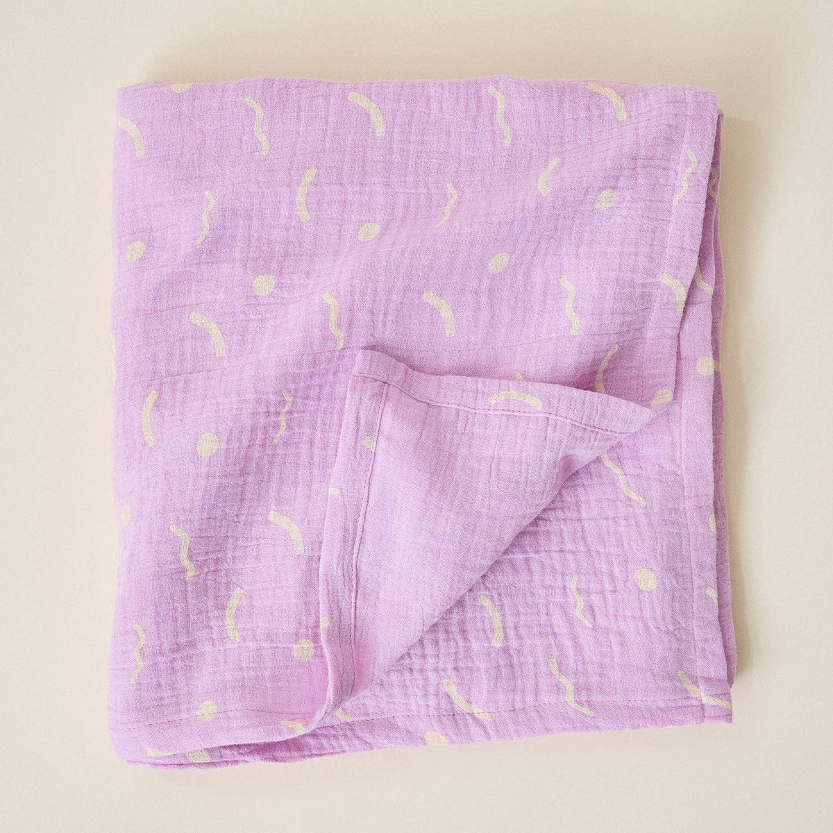 Folded purple fabric with yellow patterns on a beige background