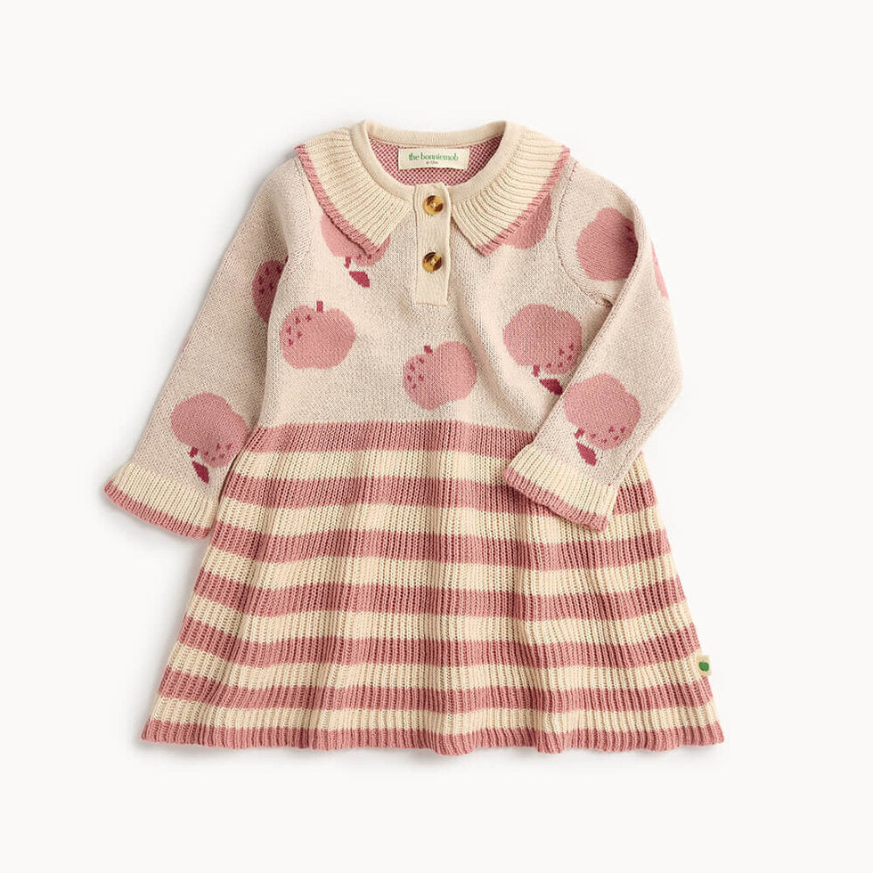 Children's dress with pink apple pattern and striped skirt on a white background