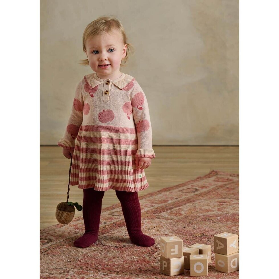 Child wearing a pink and white striped dress with a patterned background