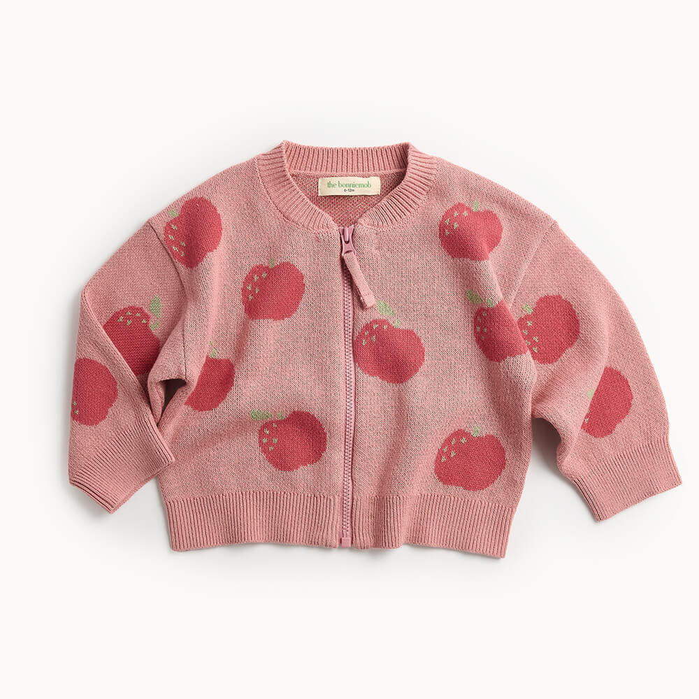 Pink children's cardigan with red apple pattern on a white background