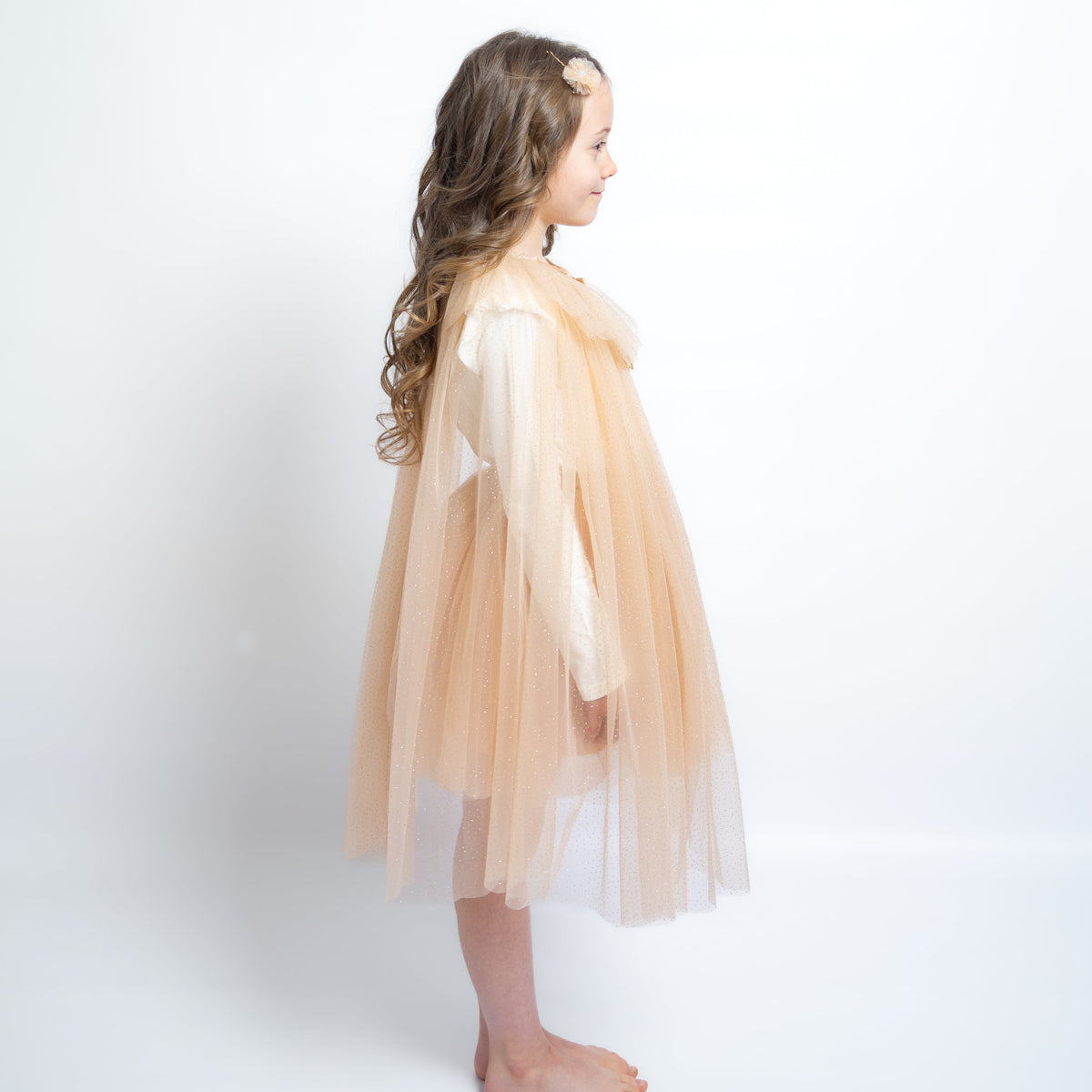 Young girl wearing a beige tulle dress against a white background