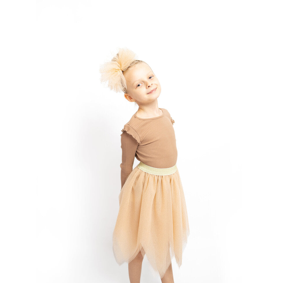 A young child modeling a two-piece costume set consisting of a brown ribbed long-sleeve top and a beige tulle tutu skirt with a lighter waistband, styled with a matching beige hair bow against a white background.