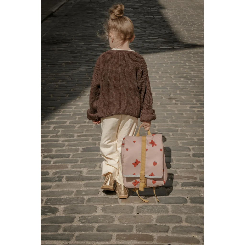 Child walking on a cobblestone street with a patterned backpack