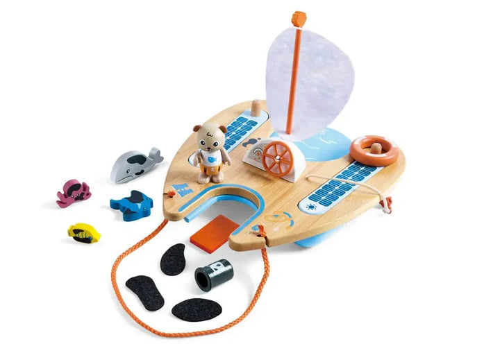 Child playing with a wooden toy boat set on a table in a bright room.