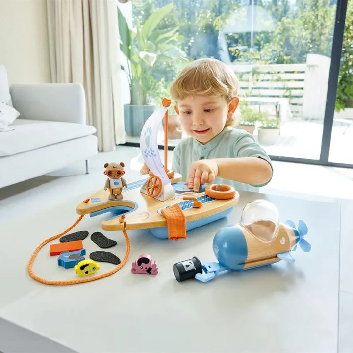 Child playing with a wooden toy boat set on a table in a bright room.