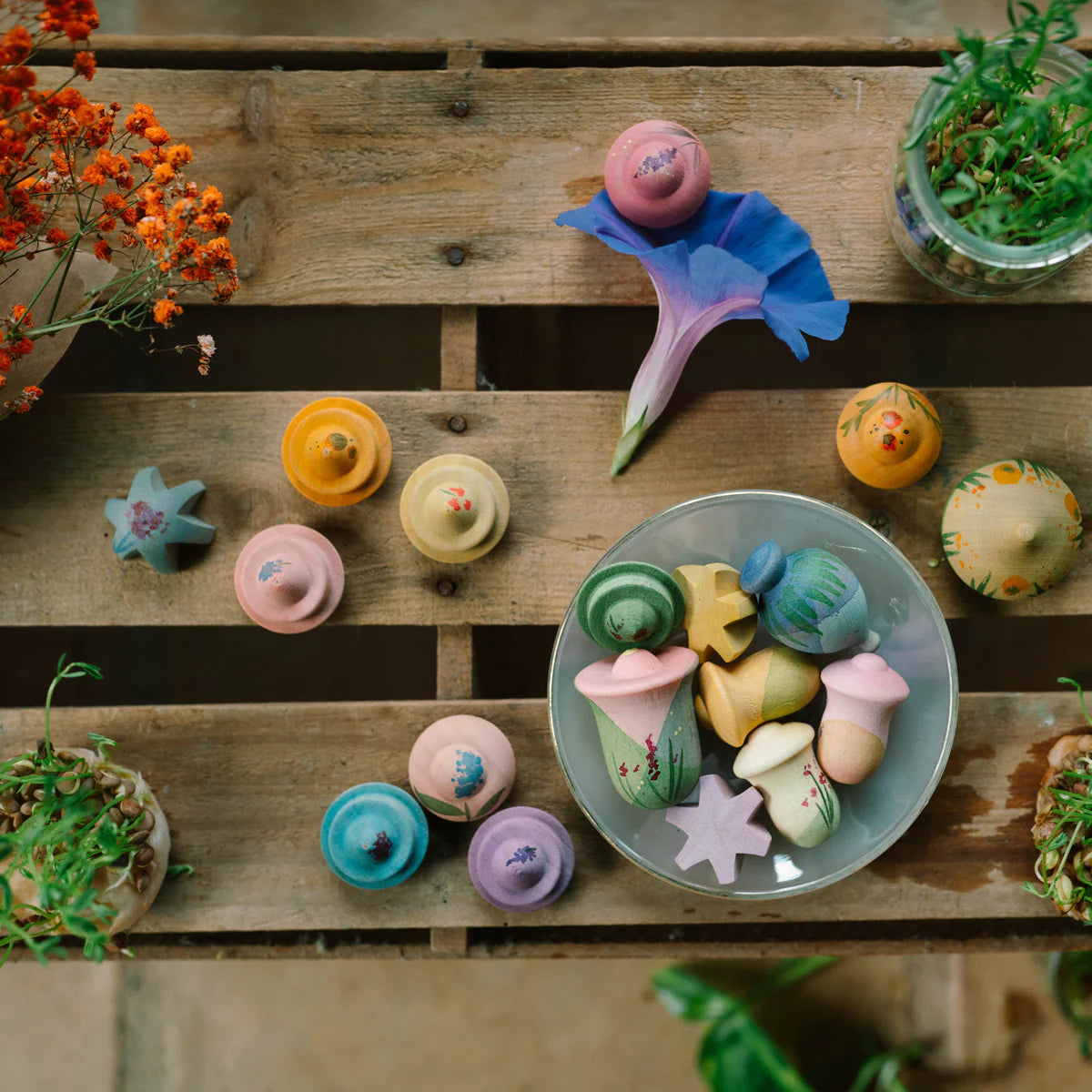 Colorful wooden flower  on a wooden surface with plants around