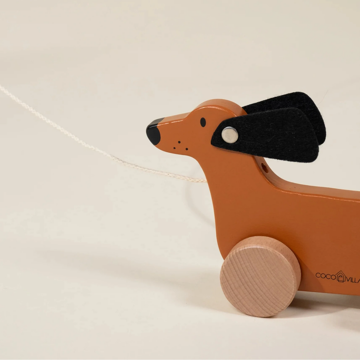 Wooden toy dachshund on wheels with a string, brand , on a beige background
