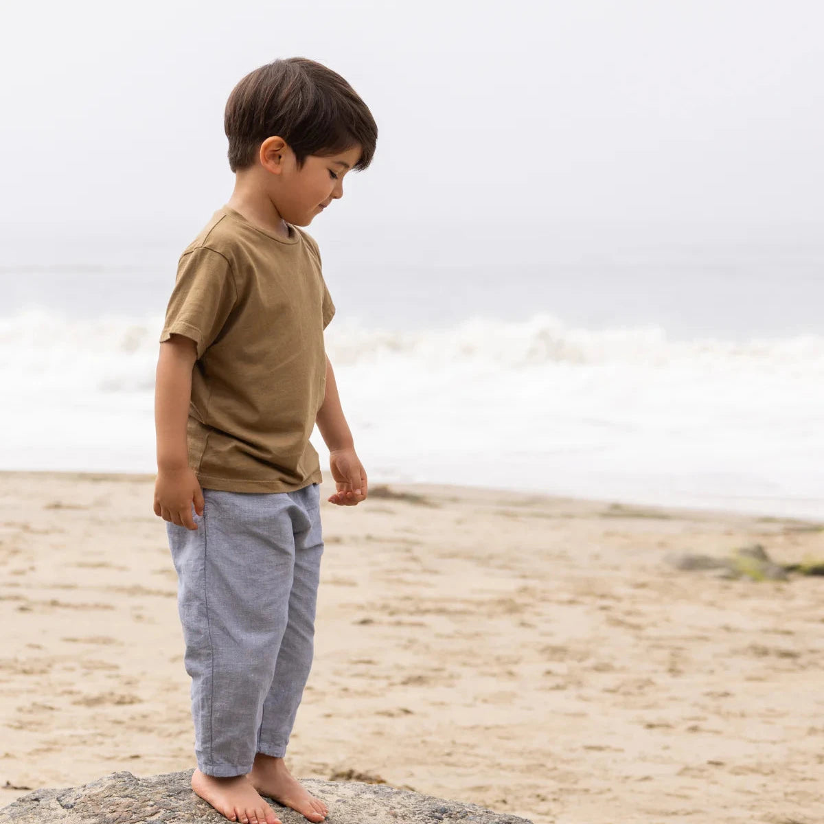 Child standing on a rock by the ocean