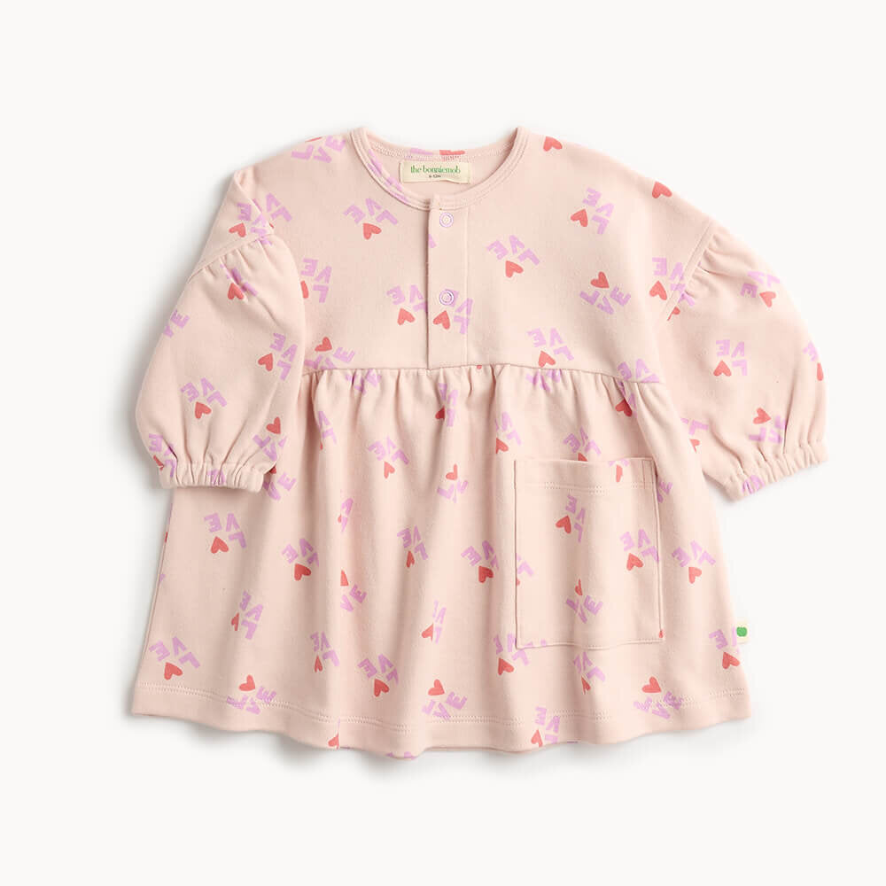 Pink children&#39;s dress with heart pattern on a white background