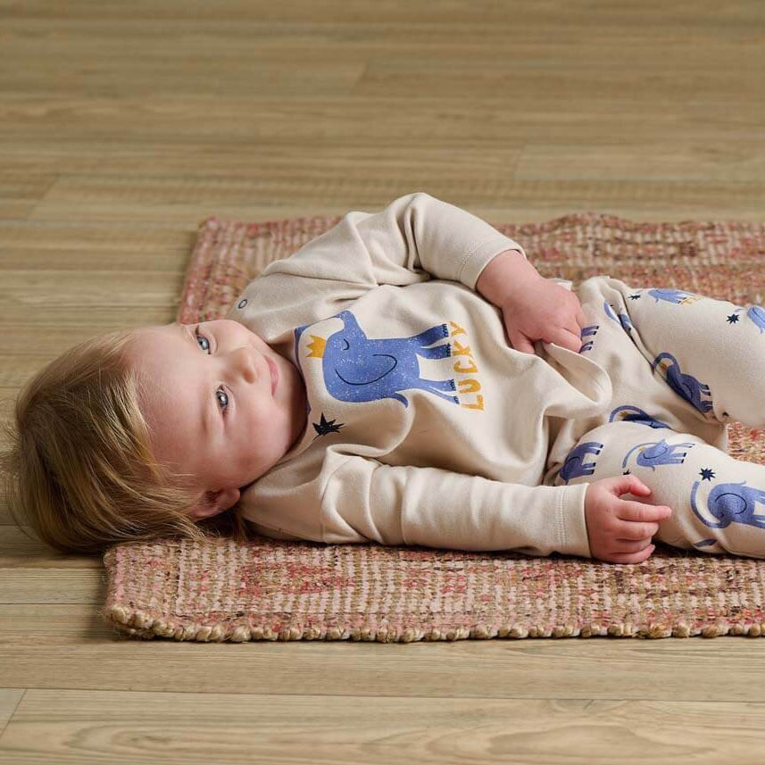 Baby lying on a rug wearing outfit with animal patterns