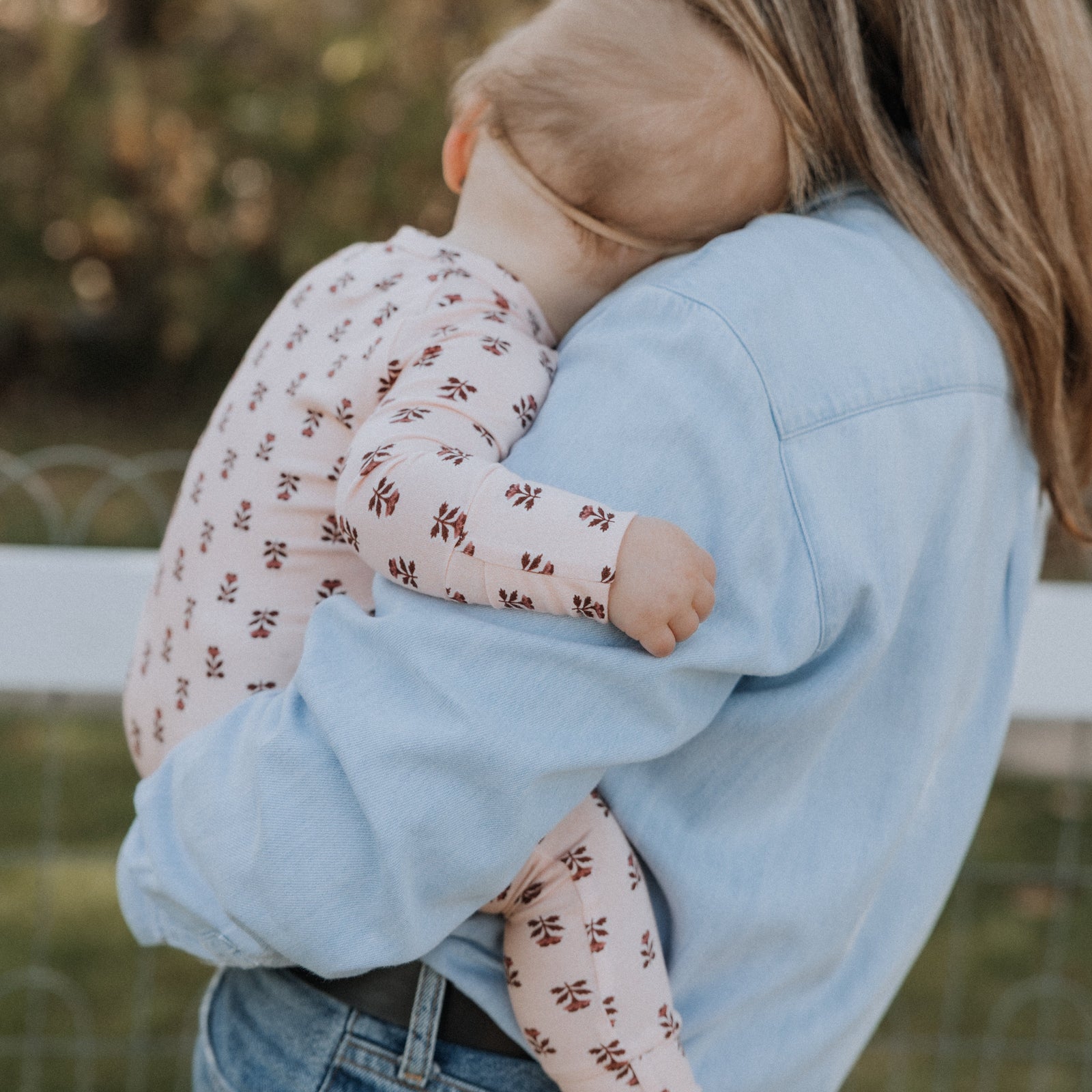 Woman holding a baby with a blurred natural background