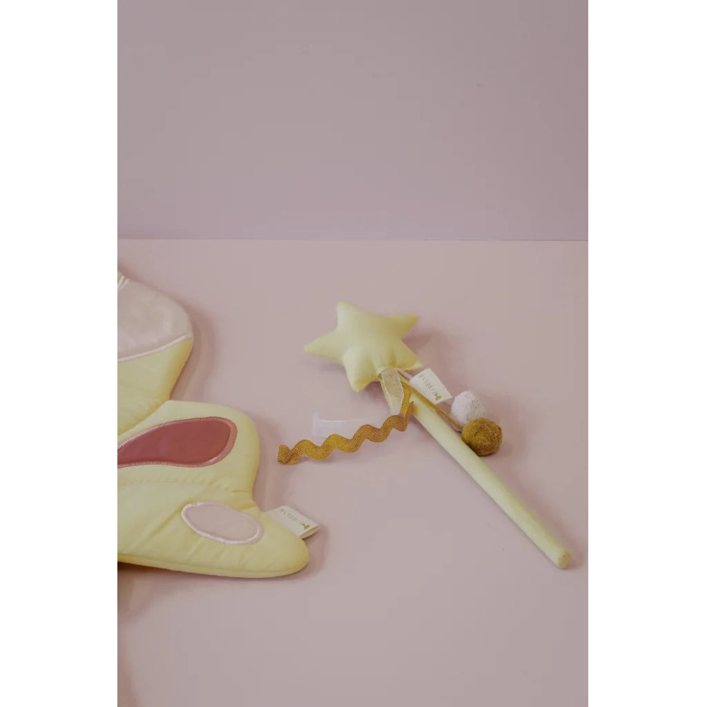 Yellow fairy wand with star tip and shoe on a pink background