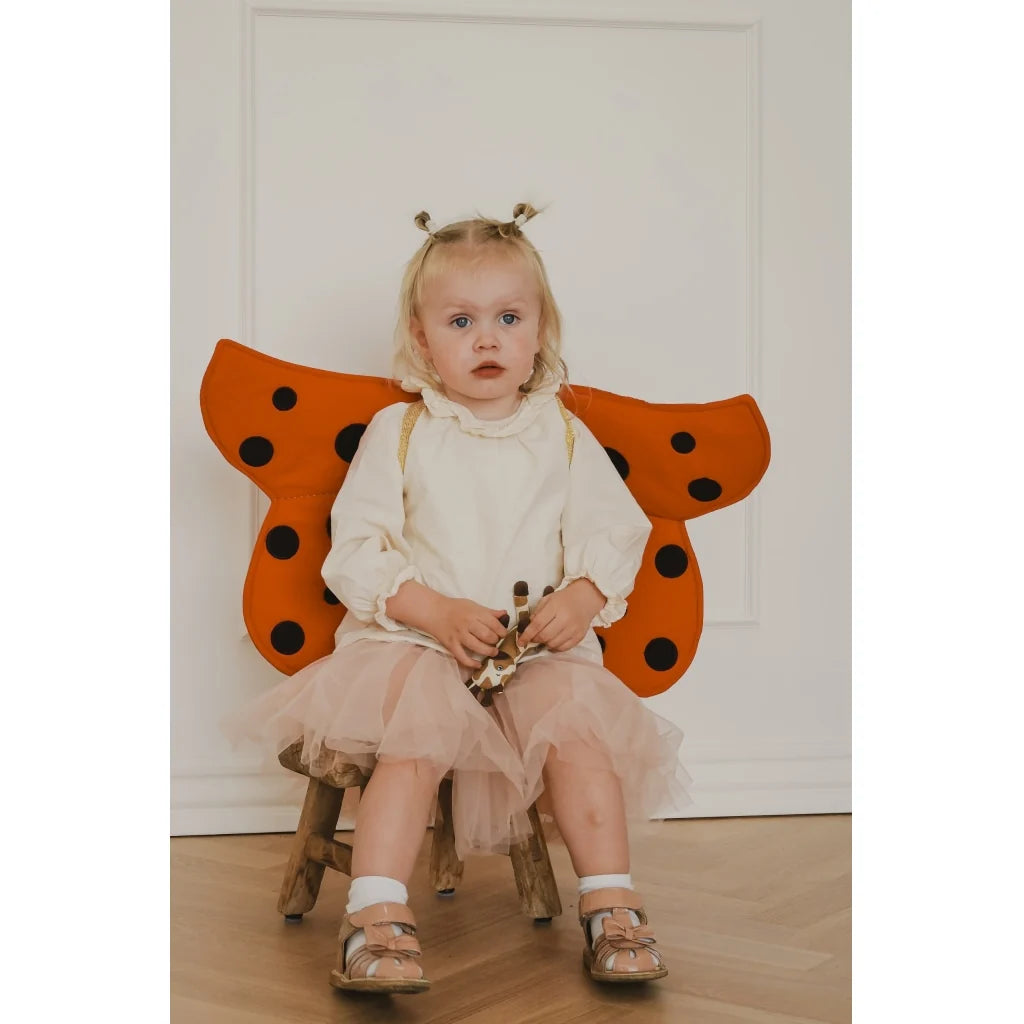 Red ladybug costume wings with black spots on a white background